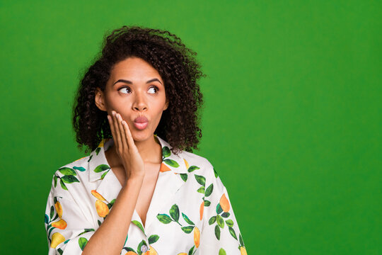 Photo of attractive young woman touch cheek look concerned empty space wear trendy orange print clothes isolated on green color background