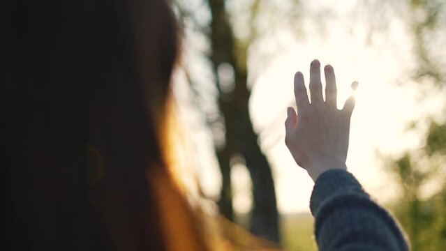Silhouette of happy dreaming girl pulls her hand to sun.Religion helping hand. Happy girl pulls her hand.Prayer in religion.Silhouette of hand in sun.Happy girl silhouette at sunset.Freedom in nature