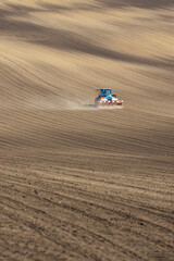 Tractor with seed drill in early spring landscape