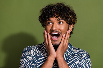 Portrait of funky young funny guy touching cheeks looking left side empty space impressed reaction...