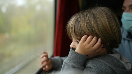 Passenger child traveling by train staring at parallel train pass by inside high speed...
