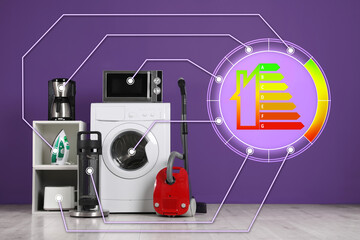 Energy efficiency rating label and different household appliances near purple wall indoors