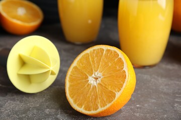 Cut fresh ripe orange, reamer and juice on grey table, closeup - obrazy, fototapety, plakaty