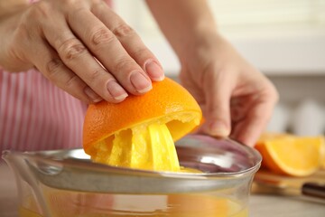 Woman squeezing orange juice at table, closeup