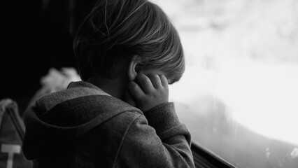 Sad thoughtful child looking down while traveling by train. Depressed passenger boy leaning on...
