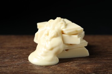 Pieces of white chocolate with tasty paste on wooden table, closeup