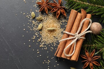 Different spices, nut and fir branches on gray table, flat lay. Space for text