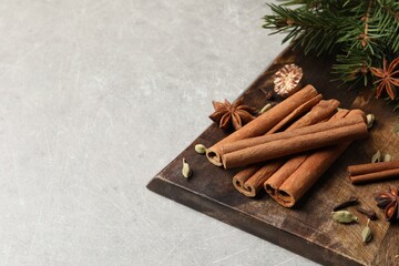 Board with different aromatic spices and fir branches on light table. Space for text