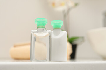 Fototapeta na wymiar Mini bottles of cosmetic products on white table against blurred background
