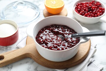 Fresh cranberry sauce in bowl served on white marble table, closeup
