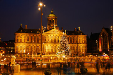 Fototapeta na wymiar Dam 2, 1012 NP Amsterdam, Netherlands - December 25, 2023: Christmas tree on Dam Square. Long exposure shot. Bluried crowd of people on the middle-ground.