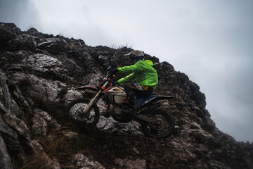 A racer at a competition rides along a cliff in rainy and gloomy weather, bottom view, professional...