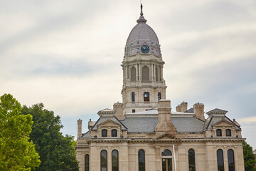 Obraz premium Classical Courthouse with Clock Tower and Lush Trees, Low Angle View