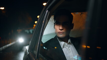 Rich businessman riding car at night closeup. Elegant passenger looking outside