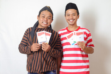 Portrait of two excited Indonesian man from Javanese and Madurese tribes holding voting paper for...