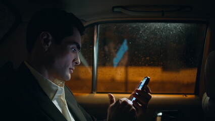 Serious boss swiping mobile phone evening auto close up. Man scrolling cellphone