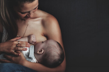 Mom breastfeeding newborn baby at home. Woman nursing baby in cozy home. Care mother spends her...