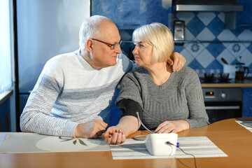 Fototapeta premium An elderly woman with hypertension measures her blood pressure at home.