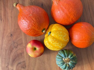 Squash and apple on a wooden table. Colorful autumn vegetables. Whole orange, yellow and green squash on a countertop.