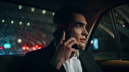 Business man talking phone in car salon closeup. Passenger looking rainy window