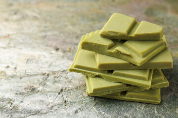Stacked pieces of tasty matcha chocolate on textured table, closeup. Space for text