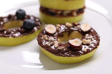Fresh apples with nut butters, blueberries and hazelnuts on plate, closeup