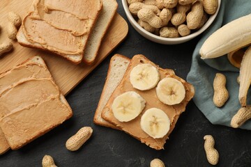 Tasty peanut butter sandwiches with sliced banana and peanuts on dark gray table, flat lay
