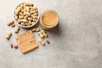 Tasty peanut butter sandwich and peanuts on gray table, flat lay. Space for text