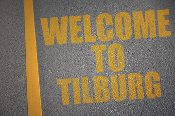 asphalt road with text welcome to Tilburg near yellow line.