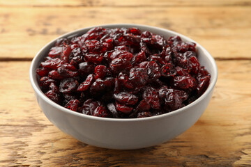 Tasty dried cranberries in bowl on wooden table, closeup