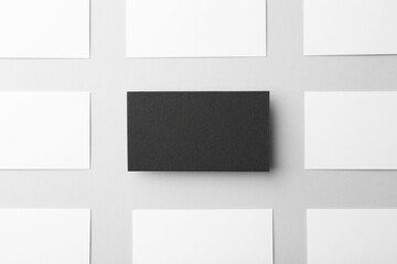 Obraz premium Blank black and white business cards on light background, flat lay. Mockup for design