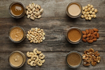 Tasty nut butters in jars and raw nuts on wooden table, flat lay