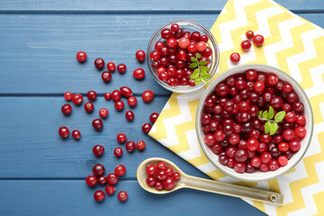 Fresh ripe cranberries in bowls and spoon on blue wooden table, flat lay