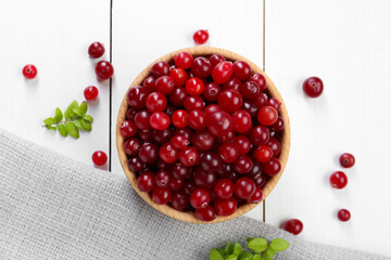 Fresh ripe cranberries and branches on white wooden table, top view