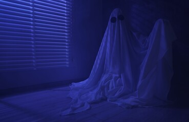 Creepy ghost. Woman covered with sheet near window in blue light, space for text