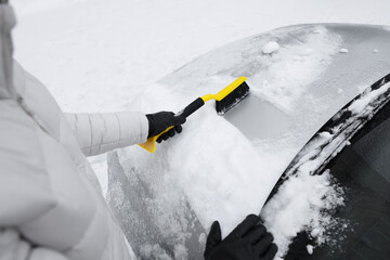 Man cleaning snow from car hood outdoors, closeup