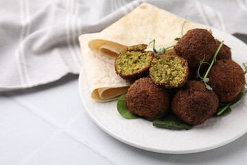 Delicious falafel balls, herbs and lavash on white table, space for text