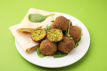 Delicious falafel balls, herbs and lavash on green background