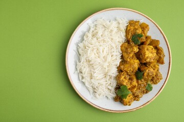 Delicious chicken curry with rice on green background, top view. Space for text