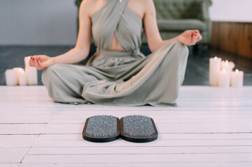 Young woman in lotus position meditates at home before standing on nails.
