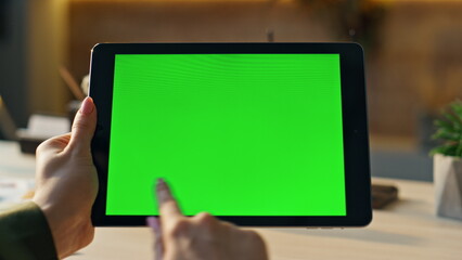 Freelancer hands swiping green screen tablet searching information at workplace.