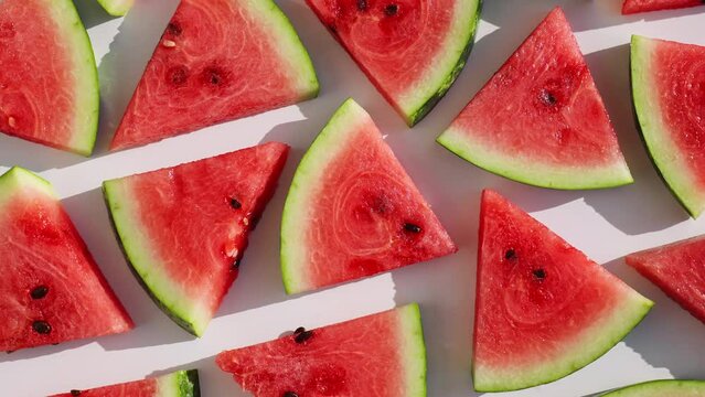 Red fresh watermelon sliced into triangles rotate in sunlight on isolated white background for your top view design. Healthy fruit berries. Summer fresh fruit snack. 