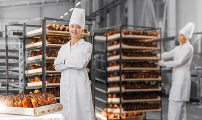 Team workers in bakery factory. Portrait woman baker in chef uniform background rack with different types of artisan craft bread