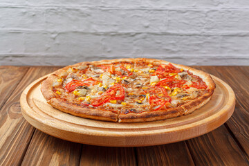 delicious pizza with chicken, mushrooms, cheese, tomatoes and corn on a wooden background