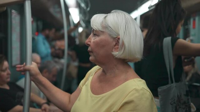 European senior 60s female standing in public transport. Beautiful woman enjoying trip at the public transport in the modern tram. High quality FullHD footage