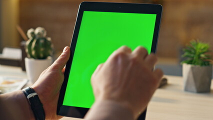 Man working mockup tablet in office close up. Male hands holding green screen