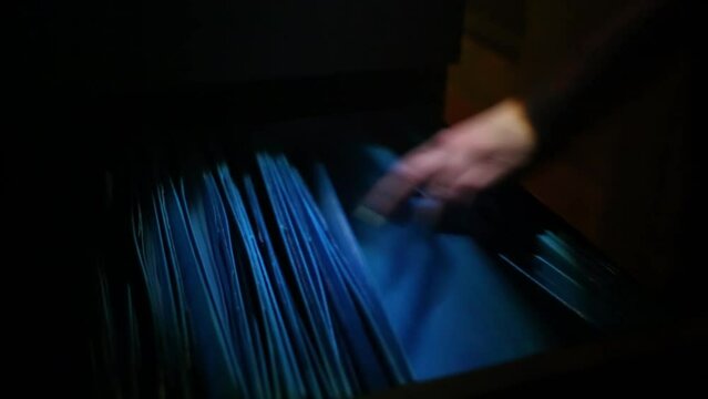Hands in darkness finding folders with papers in box on quest.