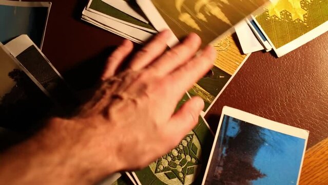 Hand touching UFO pictures and symbols in fields, on table in lamplight