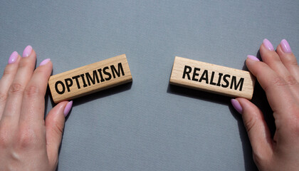 Optimism or Realism symbol. Concept word Optimism or Realism on wooden blocks. Businessman hand. Beautiful grey background. Business and Optimism or Realism concept. Copy space