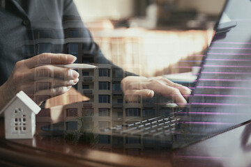 Double exposure of businessman working with laptop and house model.